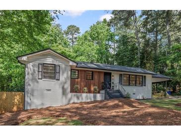 Charming white brick home with modern wood accents, black trim, and mature trees at 2238 Pinecliff Ne Dr, Atlanta, GA 30345