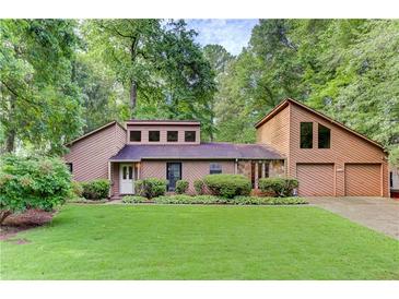Charming home featuring a 2-car garage, well-manicured lawn, and mature trees at 4920 Tremont Ne Dr, Marietta, GA 30066