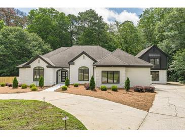 Stunning white brick home with dark trim, manicured lawn, and a circular driveway at 6394 Wood Valley Rd, Douglasville, GA 30134