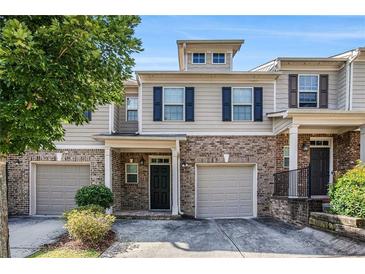 Charming townhome featuring a brick facade, gray siding, and attached one-car garage at 2725 Morgan Glen Rd, Buford, GA 30519