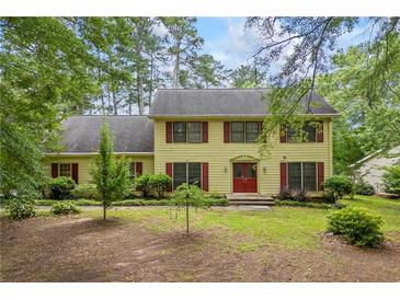 Charming yellow two-story home with red shutters and a well-manicured front yard surrounded by mature trees at 705 Clubhouse Se Dr, Conyers, GA 30094