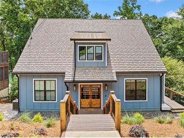 Charming two-story blue home with a wooden entryway and manicured landscaping in a wooded setting at 6900 Driskell Cir, Cumming, GA 30041