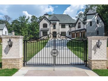 Grand gated entrance with white brick columns and a sweeping drive leading to a luxurious white brick home at 10745 Shallowford Rd, Roswell, GA 30075