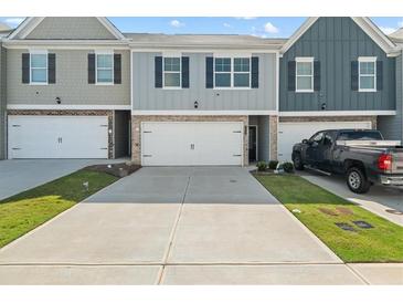 Charming townhome exterior with attached garages and a neatly maintained front lawn in a vibrant community at 11640 Mendenhall Ct, Hampton, GA 30228