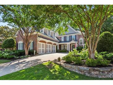 Stately brick home with a three-car garage, manicured landscaping, and mature trees providing shade at 1382 Murrays Loch Nw Pl, Kennesaw, GA 30152