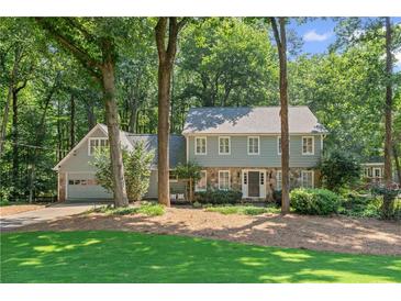Charming two-story home with a stone facade and attached garage nestled among mature trees at 220 Hollyridge Dr, Roswell, GA 30076