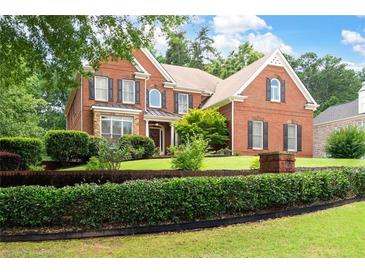Charming brick home with manicured lawn and mature landscaping featuring black window shutters at 3045 Moss Stone Lane Sw Ln, Marietta, GA 30064