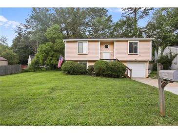 Split-level home boasting a neat lawn, tidy shrubbery and an American flag at 1271 Muirforest Ln, Stone Mountain, GA 30088