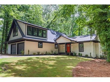 Charming home with a two-car garage, black framed windows, a bright red front door, and verdant landscaping at 6486 Aquila Dr, Morrow, GA 30260