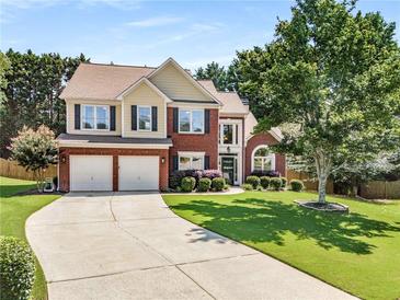 Charming two-story home with a well-manicured lawn, complemented by a two-car garage and inviting brick facade at 2740 Greymont Ct, Cumming, GA 30041