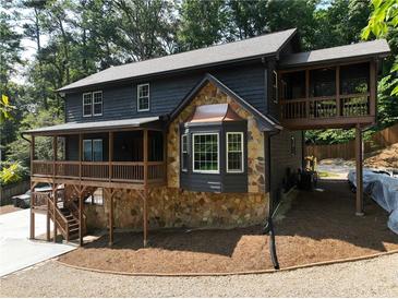 Stunning two-story home featuring a stone foundation, covered porch, and an elevated sunroom with wooded views at 260 Lakemont Dr, Roswell, GA 30075