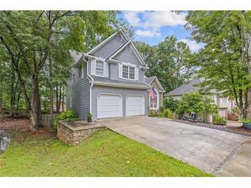 Charming two-story home with a two-car garage and well-manicured lawn in a lush, wooded setting at 722 Ivory Trl, Woodstock, GA 30188