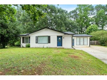 Charming white-brick home with a well-manicured lawn and a bright blue front door at 1694 Pheasant Dr, Atlanta, GA 30238