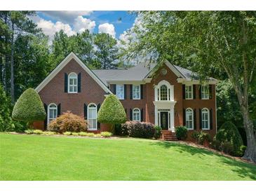 Charming two-story brick home with manicured lawn, mature trees, and inviting front entrance at 1464 Chatsworth Trace, Lawrenceville, GA 30044