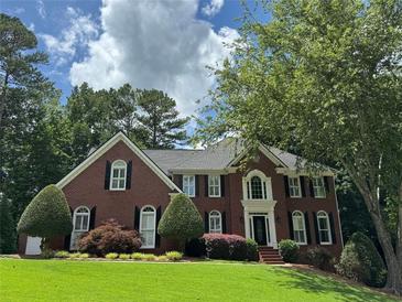 Charming two-story brick home with a well-manicured lawn and mature trees at 1464 Chatsworth Trace, Lawrenceville, GA 30044