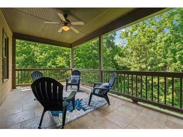 Relaxing covered patio with a ceiling fan and outdoor seating overlooking lush greenery at 3405 Camellia Ln, Suwanee, GA 30024