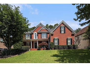 Charming brick home featuring a manicured lawn and traditional architectural details at 351 Prestbury Ct, Suwanee, GA 30024