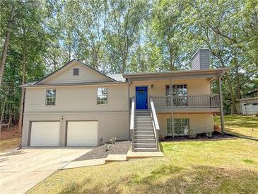 Charming home featuring a two-car garage, light beige siding and a welcoming blue front door at 90 Lake Avalon Ct, Dallas, GA 30157