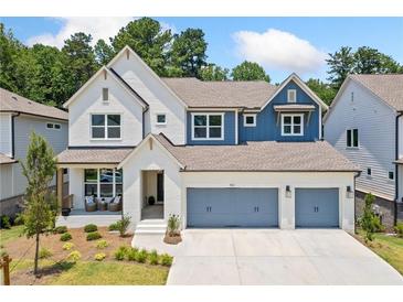Charming two-story home featuring a three-car garage, white brick, and manicured landscaping at 461 Maypop Ln, Woodstock, GA 30188