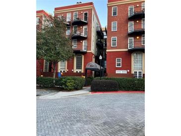 Condominium exterior showcasing its brick facade, black iron balconies, and landscaped entrance with covered walkway at 2840 Peachtree Road Nw Nw Rd # 306, Atlanta, GA 30305