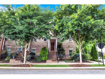 Brick townhouse with meticulously maintained landscaping, sidewalk, and mature trees at 326 Brownstones Ne Cir, Atlanta, GA 30312