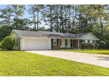 Charming single-story home with a well-manicured lawn, attached two car garage, and mature trees at 4149 Indian Lake Cir, Stone Mountain, GA 30083