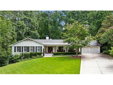 Charming home with a well-manicured lawn, mature trees, and a welcoming facade, complete with a three car garage at 6175 Weatherly Dr, Sandy Springs, GA 30328