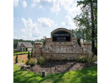 Stone community entrance sign for Streamwood Manor, featuring manicured landscaping and a glimpse of new homes at 15 Regal Ln, Covington, GA 30016