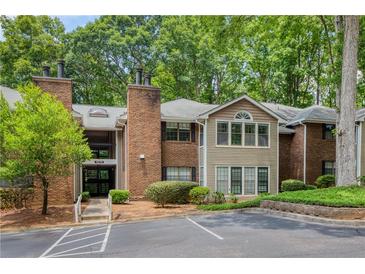 Exterior view of a brick and siding condo building with mature trees at 107 Barrington Hills Dr, Atlanta, GA 30350