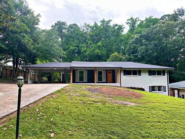 Charming single-story home with a lush front yard and driveway leading to a covered carport at 6456 Wright Ne Rd, Atlanta, GA 30328