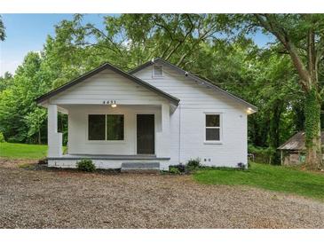 Charming white-painted home with a covered front porch and lush landscaping, offering curb appeal at 4451 Flat Shoals Pkwy, Decatur, GA 30034