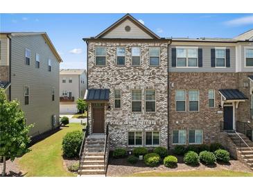 Charming townhome featuring a mix of brick and stone, a covered porch, and professional landscaping at 4458 Dunblane Ave, Sugar Hill, GA 30518