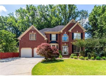 Traditional brick home showcasing an attached two-car garage and meticulously maintained front yard at 5287 Wild Indigo Way, Acworth, GA 30102