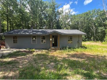 Charming one-story home with a gray exterior and classic architectural details, surrounded by lush greenery and a well-maintained lawn at 4601 Wilson James Sw Rd, Atlanta, GA 30331