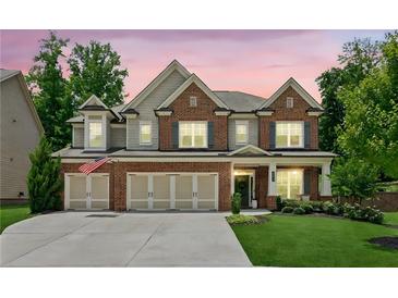 Charming two-story brick home with a three-car garage and well-manicured lawn at twilight at 4972 Park Vale Dr, Sugar Hill, GA 30518