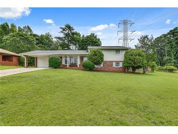 Charming home featuring a well-maintained lawn, a brick facade, and a convenient carport at 5440 Huron Dr, Lake City, GA 30260