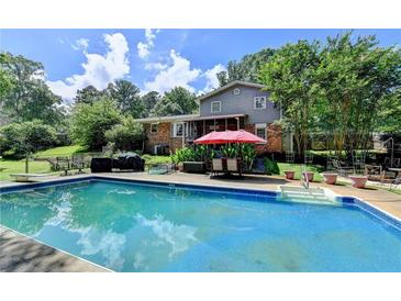Inviting backyard pool with lounge chairs and umbrella, perfect for relaxing and entertaining outdoors at 4562 Lucerne Valley Sw Rd, Lilburn, GA 30047