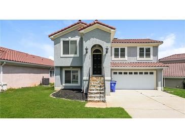 Charming stucco home featuring a red tile roof, well-kept lawn, and a two-car garage at 113 Garden Walk, Stockbridge, GA 30281