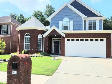 Charming two-story home featuring a two-car garage, brick accents, and a manicured lawn at 3473 Newtons Crest Cir, Snellville, GA 30078
