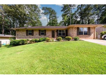 Charming brick ranch with a well-maintained front lawn, shrubs, and a paved driveway at 1472 High Meadow Dr, Stone Mountain, GA 30083