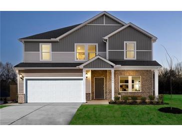 Two-story home featuring a two-car garage, brick facade, manicured lawn, and welcoming entryway at 1921 Fairchild Ln, Grayson, GA 30017