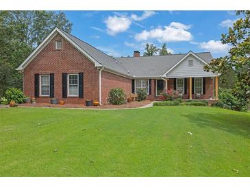 Charming brick home featuring a lush front lawn, mature trees, and inviting front porch at 3992 Spot Rd, Cumming, GA 30040