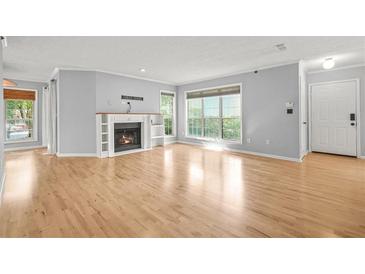 Spacious living room featuring a fireplace, hardwood floors, and natural light from large windows at 305 Mill Pond Se Ct, Smyrna, GA 30082