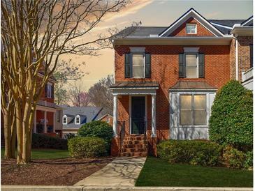 Inviting brick two-story townhome with landscaped front yard and walkway to a covered front door at 5210 Davenport Pl, Roswell, GA 30075