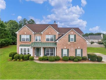 Charming two-story brick home with a well-manicured lawn and lush green landscaping at 1613 Brolington Ct, Conyers, GA 30013