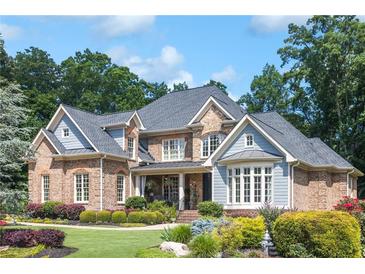 Attractive brick and blue paneled two-story home with manicured lawn, garden beds, and mature shade trees at 217 Fernwood Pl, Woodstock, GA 30188