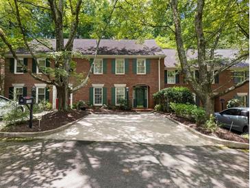 Charming brick townhome featuring a driveway and surrounded by mature trees at 1355 E Rock Springs Ne Rd, Atlanta, GA 30306