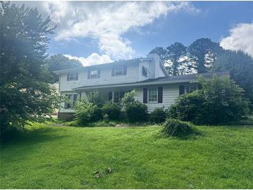 Traditional two-story home with a lush green lawn and mature trees providing shade at 713 Pine Chase Ct, Lawrenceville, GA 30043