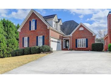 Charming red brick home featuring blue shutters, manicured landscaping, and a two-car garage at 2324 Blackberry Ct, Snellville, GA 30078