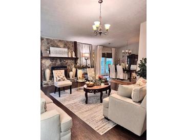Comfortable living room with stone fireplace and elegant chandelier creating a warm and inviting atmosphere at 791 Bristol Way, Lithonia, GA 30058